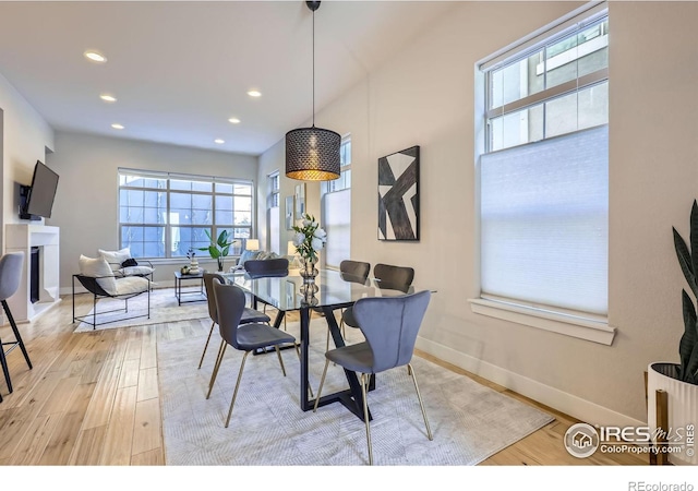 dining area with light wood finished floors, recessed lighting, a fireplace, and baseboards