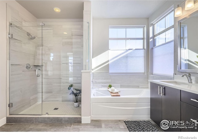 bathroom with a garden tub, vanity, and a stall shower