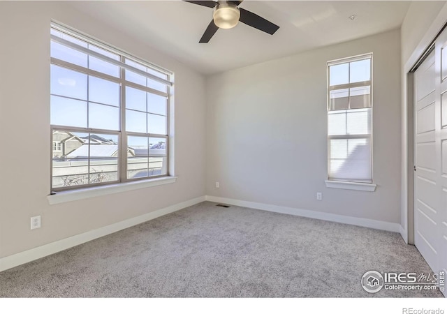 carpeted empty room featuring visible vents, ceiling fan, and baseboards