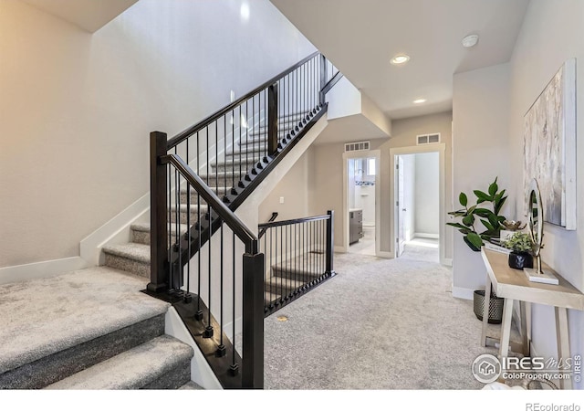 staircase featuring baseboards, visible vents, and carpet flooring