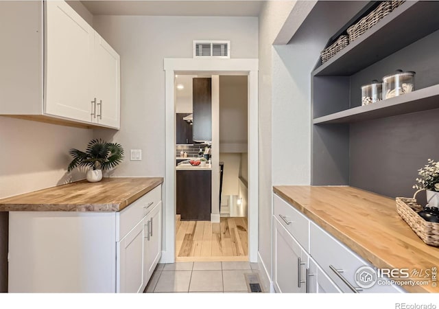 kitchen featuring white cabinetry, butcher block counters, visible vents, and open shelves