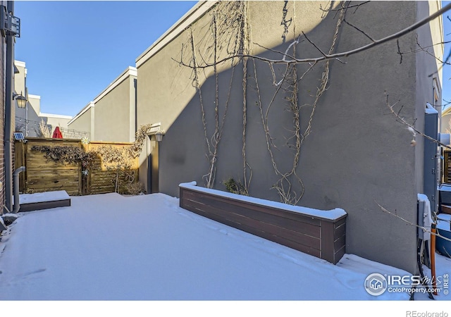 view of snowy exterior with stucco siding