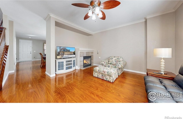 7145 Brittany Dr, Fort Collins, CO 80525 - living area with a ceiling fan, wood finished floors, a tiled fireplace, ornamental molding, and baseboards
