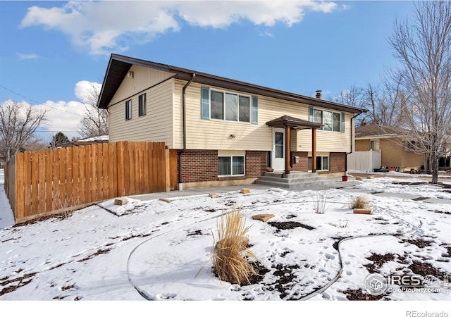 raised ranch with fence and brick siding