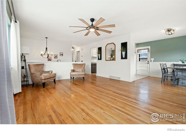 interior space featuring light wood-style floors, visible vents, baseboards, and ceiling fan with notable chandelier