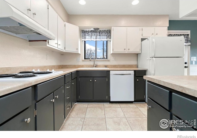 kitchen with white appliances, under cabinet range hood, white cabinets, and a sink