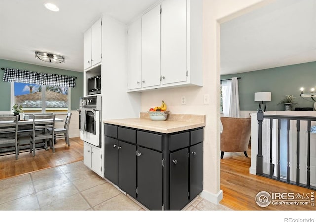 kitchen with light wood-style floors, white cabinetry, appliances with stainless steel finishes, and light countertops