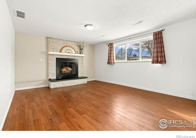 unfurnished living room featuring a fireplace, wood finished floors, and visible vents