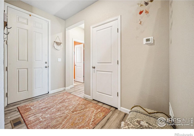 foyer entrance featuring light wood-type flooring, baseboards, and visible vents