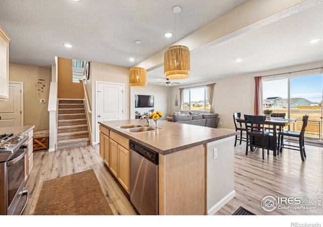 kitchen featuring light wood finished floors, appliances with stainless steel finishes, a sink, and a center island with sink