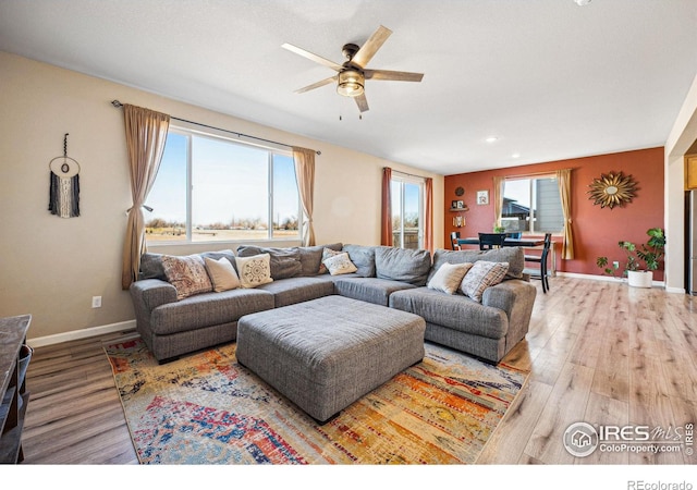 living area featuring ceiling fan, baseboards, and wood finished floors