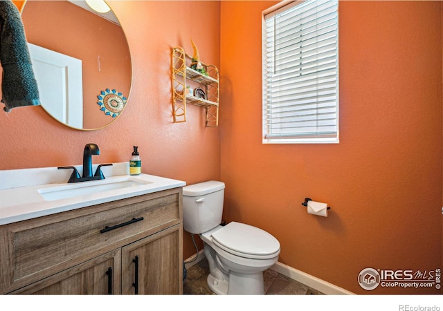 half bath with vanity, toilet, and baseboards