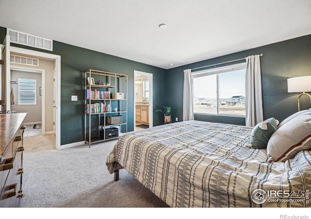 carpeted bedroom with visible vents, baseboards, and ensuite bathroom