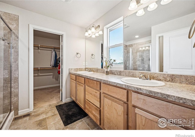 full bath featuring visible vents, a sink, a shower stall, and a spacious closet