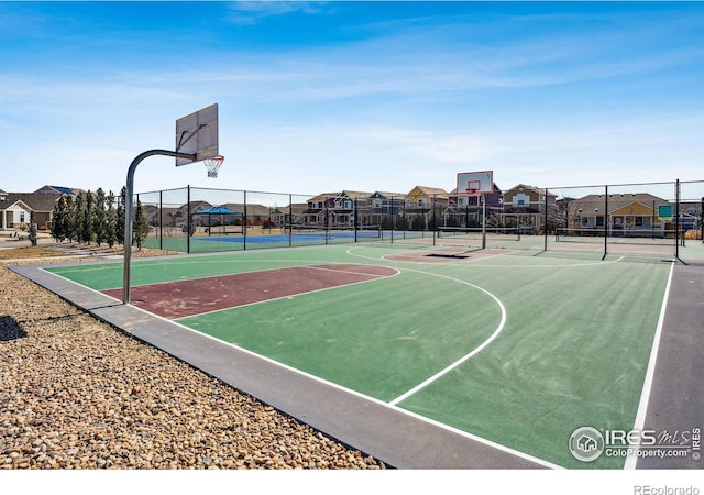 view of basketball court featuring community basketball court, fence, and a residential view