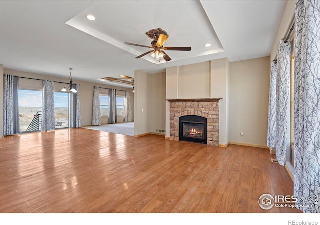 unfurnished living room with a fireplace, recessed lighting, a raised ceiling, ceiling fan, and wood finished floors