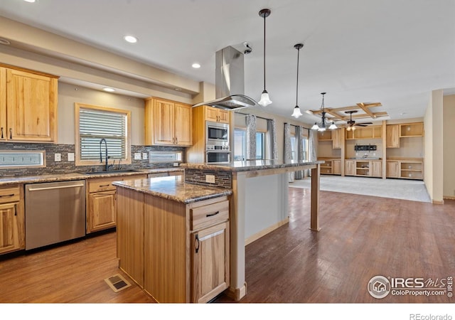 kitchen with island range hood, a sink, visible vents, appliances with stainless steel finishes, and light brown cabinetry