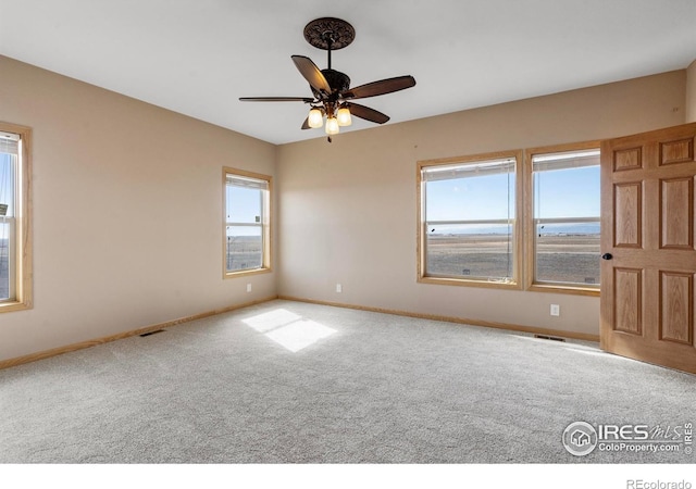 spare room featuring visible vents, carpet floors, a ceiling fan, and baseboards