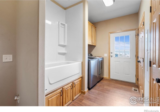 laundry room featuring visible vents, light wood-style flooring, washing machine and dryer, and cabinet space