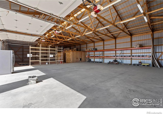 garage with metal wall, freestanding refrigerator, and a garage door opener