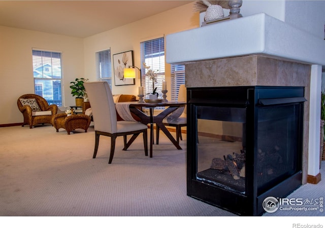 sitting room featuring baseboards, carpet flooring, and a multi sided fireplace