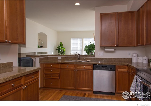 kitchen featuring brown cabinetry, dishwasher, and a sink