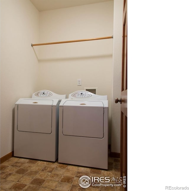 clothes washing area featuring baseboards, laundry area, washing machine and clothes dryer, and stone finish flooring