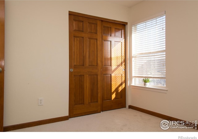 unfurnished bedroom featuring light colored carpet and baseboards