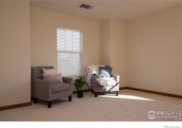 sitting room with carpet floors, visible vents, and baseboards