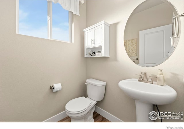 half bath featuring toilet, baseboards, and wood finished floors