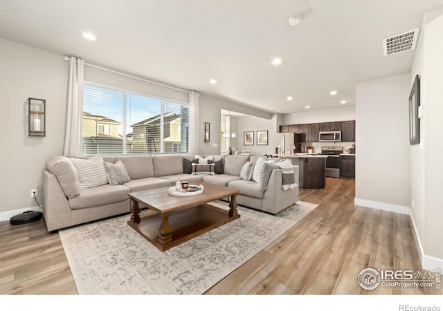 living area with light wood-style flooring, visible vents, baseboards, and recessed lighting