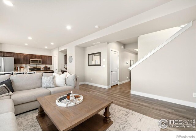 living room featuring light wood-type flooring, baseboards, and recessed lighting