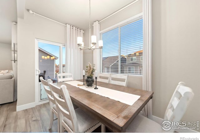 dining room with baseboards, wood finished floors, and a notable chandelier