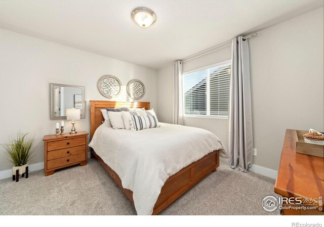 bedroom featuring light carpet and baseboards