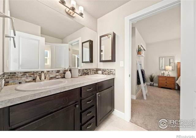 bathroom with connected bathroom, a sink, decorative backsplash, and double vanity