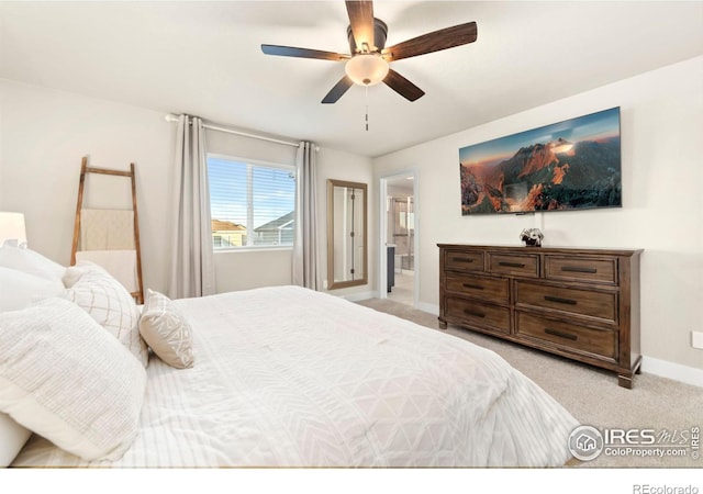 bedroom featuring a ceiling fan, light carpet, baseboards, and ensuite bathroom