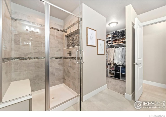 full bath with a shower stall, a walk in closet, and baseboards