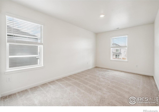 carpeted empty room featuring baseboards