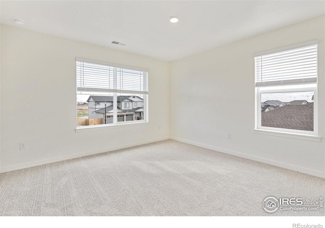 carpeted empty room featuring baseboards and visible vents