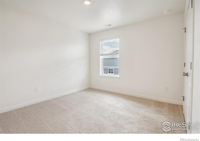 empty room with carpet, visible vents, and baseboards