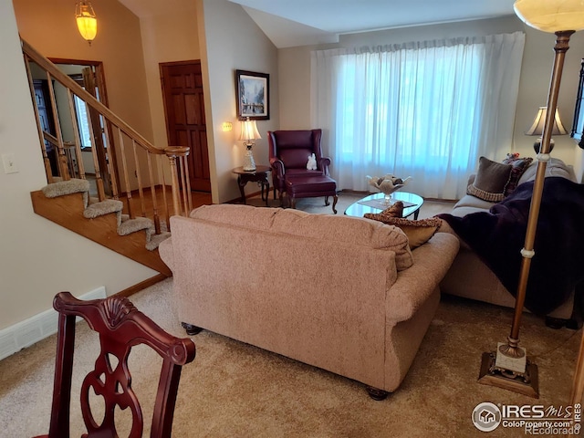 carpeted living room with lofted ceiling and stairway