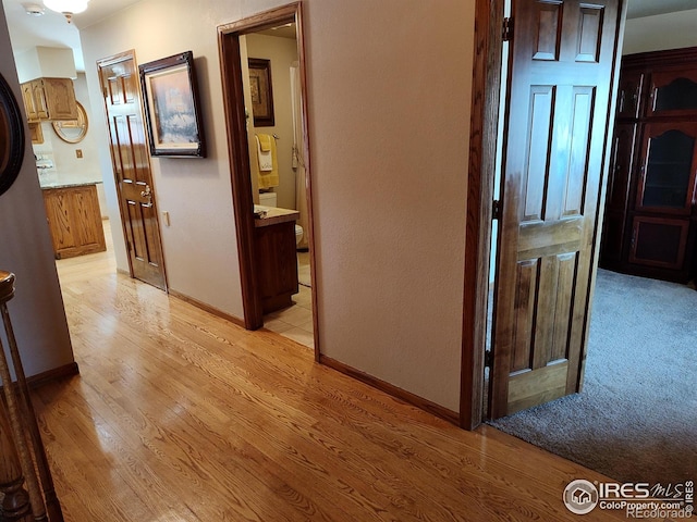 hall featuring light wood-type flooring and baseboards