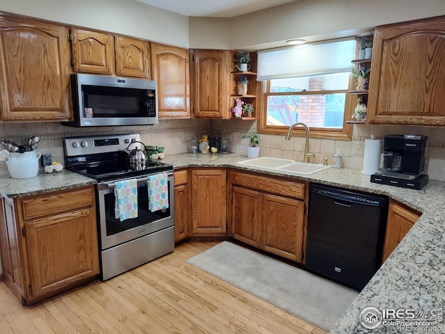 kitchen featuring appliances with stainless steel finishes, light wood-style floors, a sink, and open shelves