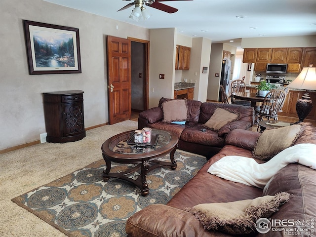 living area with ceiling fan, carpet, and baseboards