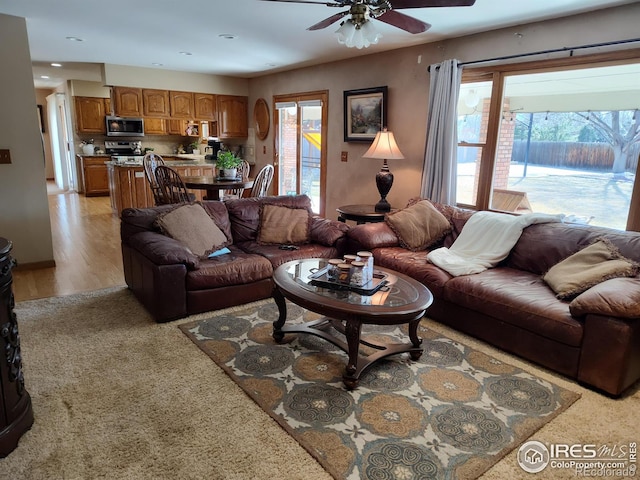 living area featuring a healthy amount of sunlight, light wood-style floors, and a ceiling fan