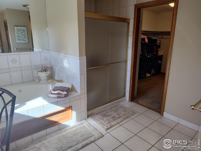 bathroom with a stall shower, a walk in closet, a garden tub, and tile patterned floors