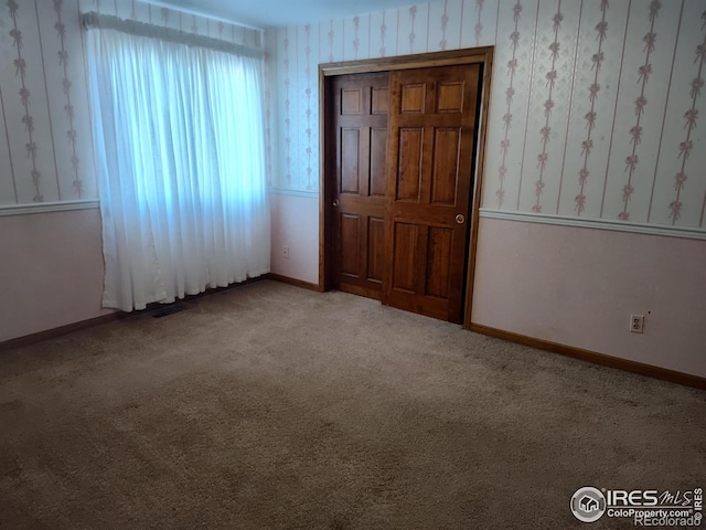 carpeted spare room with wallpapered walls and baseboards