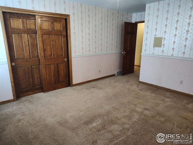 unfurnished bedroom featuring baseboards, carpet floors, visible vents, and wallpapered walls