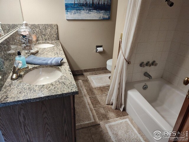 bathroom with double vanity, shower / tub combo, a sink, and toilet