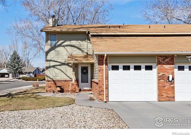 view of front of house featuring brick siding, driveway, and a chimney